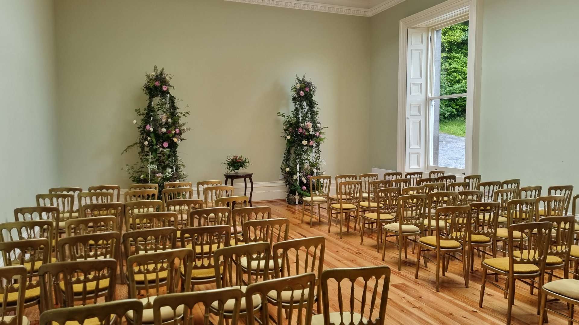 The ceremony room at Temple House set with gilt chairs and floral arches